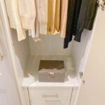 Cardigans organised from light to dark in a wardrobe.